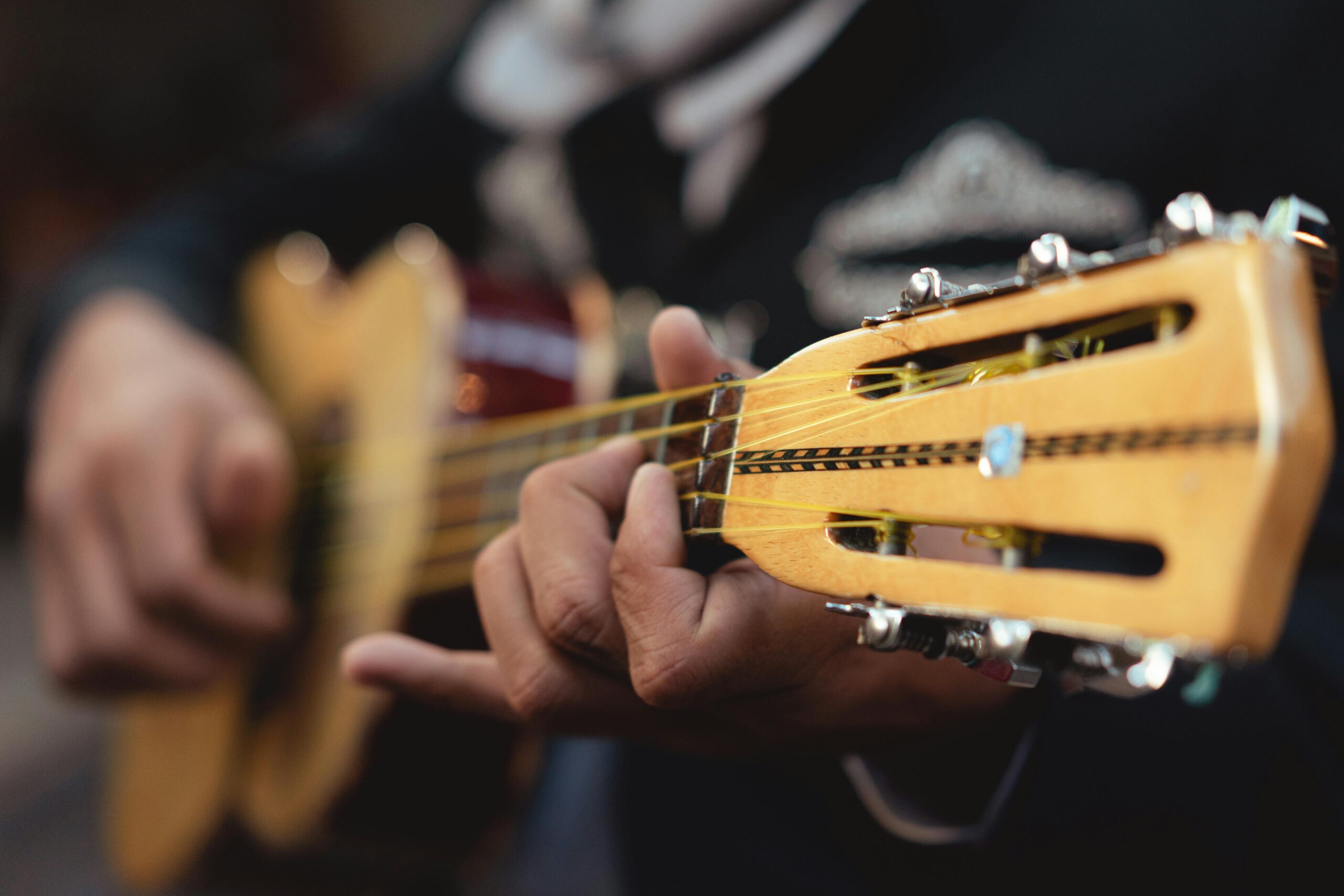 Detailed close-up of a mariachi musician playing a string guitar, showcasing skill and tradition.